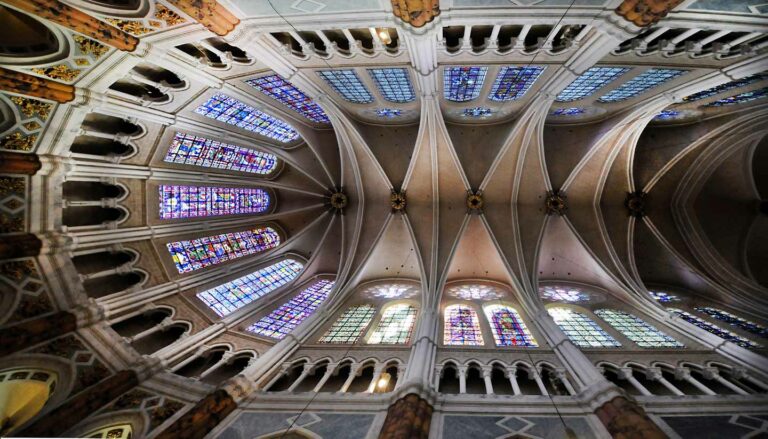 Interior view of the Cathedral of Notre-Dame de Chartres, showcasing its intricate Gothic architecture and vibrant stained glass windows, a famous tourist attraction in France.