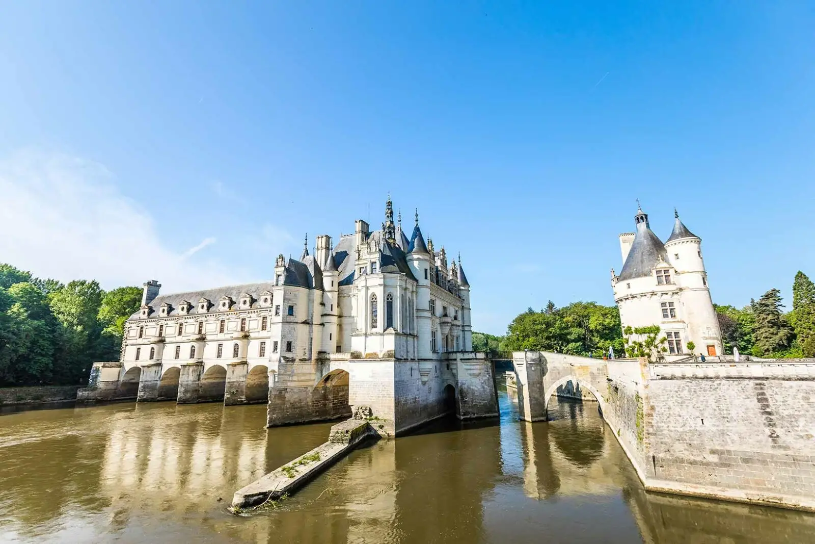 Château de Chenonceau, a historic castle spanning the River Cher in Chenonceaux, France, under clear blue skies.