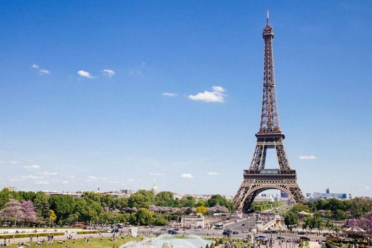 Scenic view of the Eiffel Tower in Paris with clear skies and bustling tourists visiting iconic French landmark