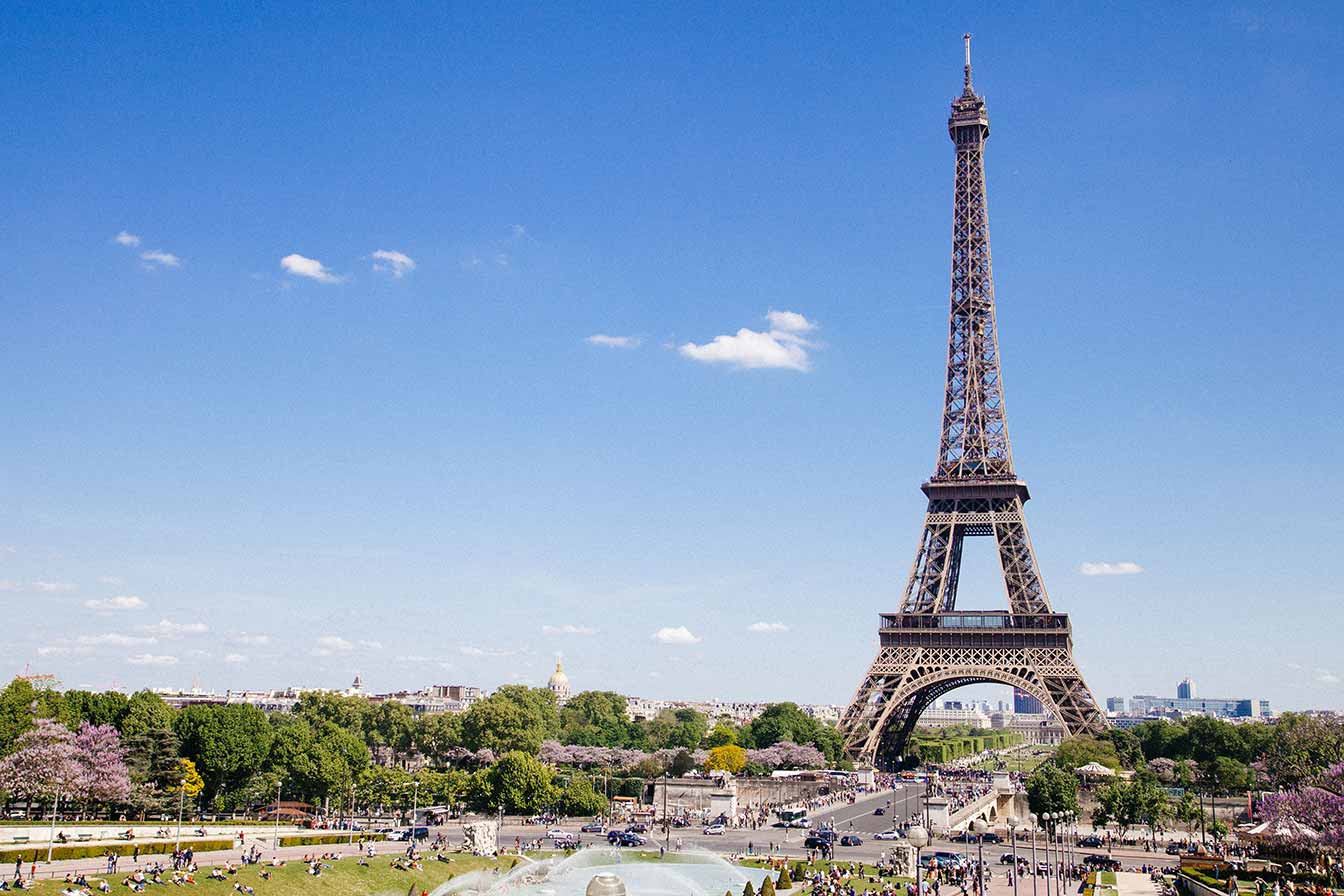 Scenic view of the Eiffel Tower in Paris with clear skies and bustling tourists visiting iconic French landmark