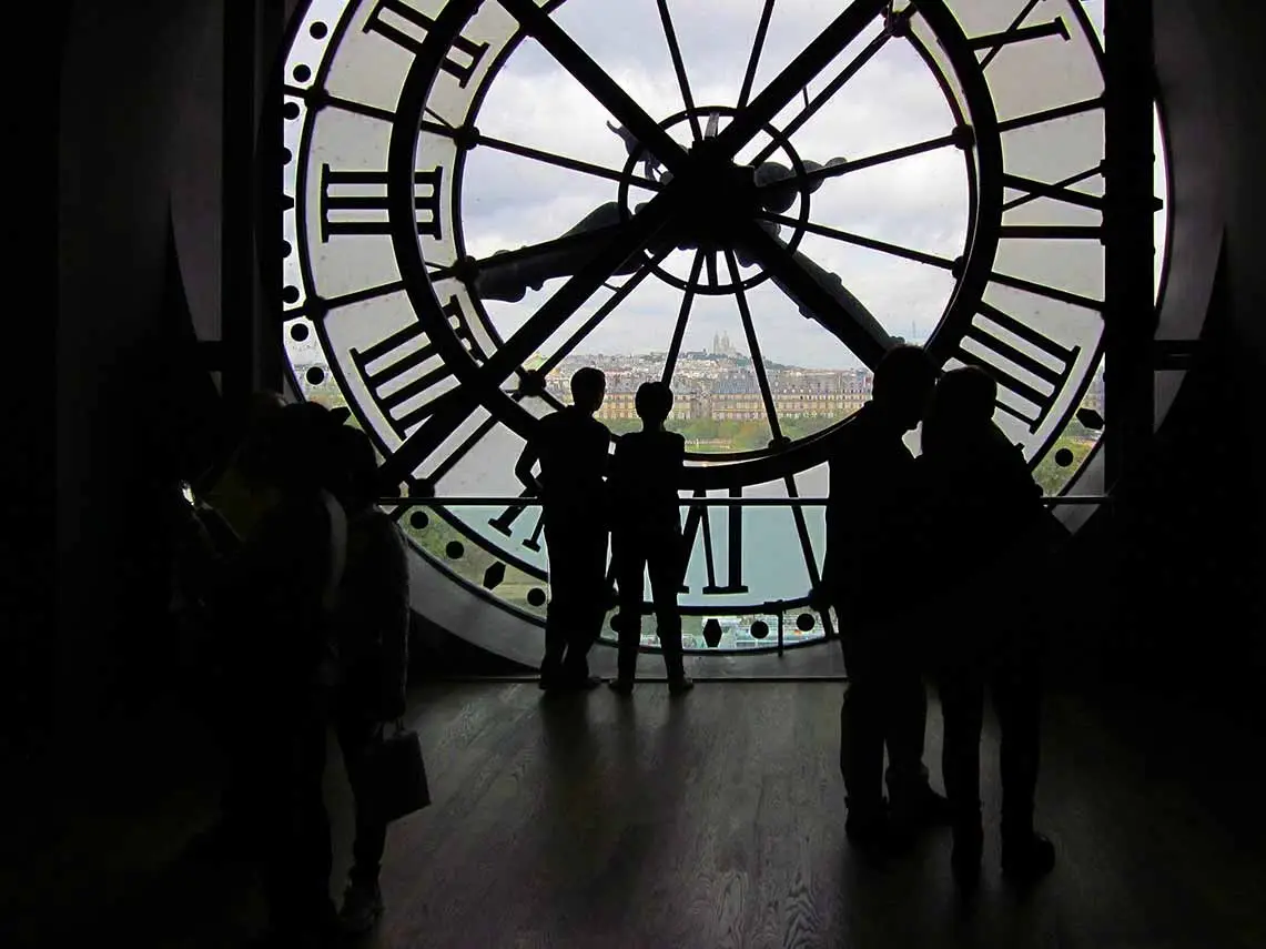 couple looking through glass clockface in Musée d'Orsay,