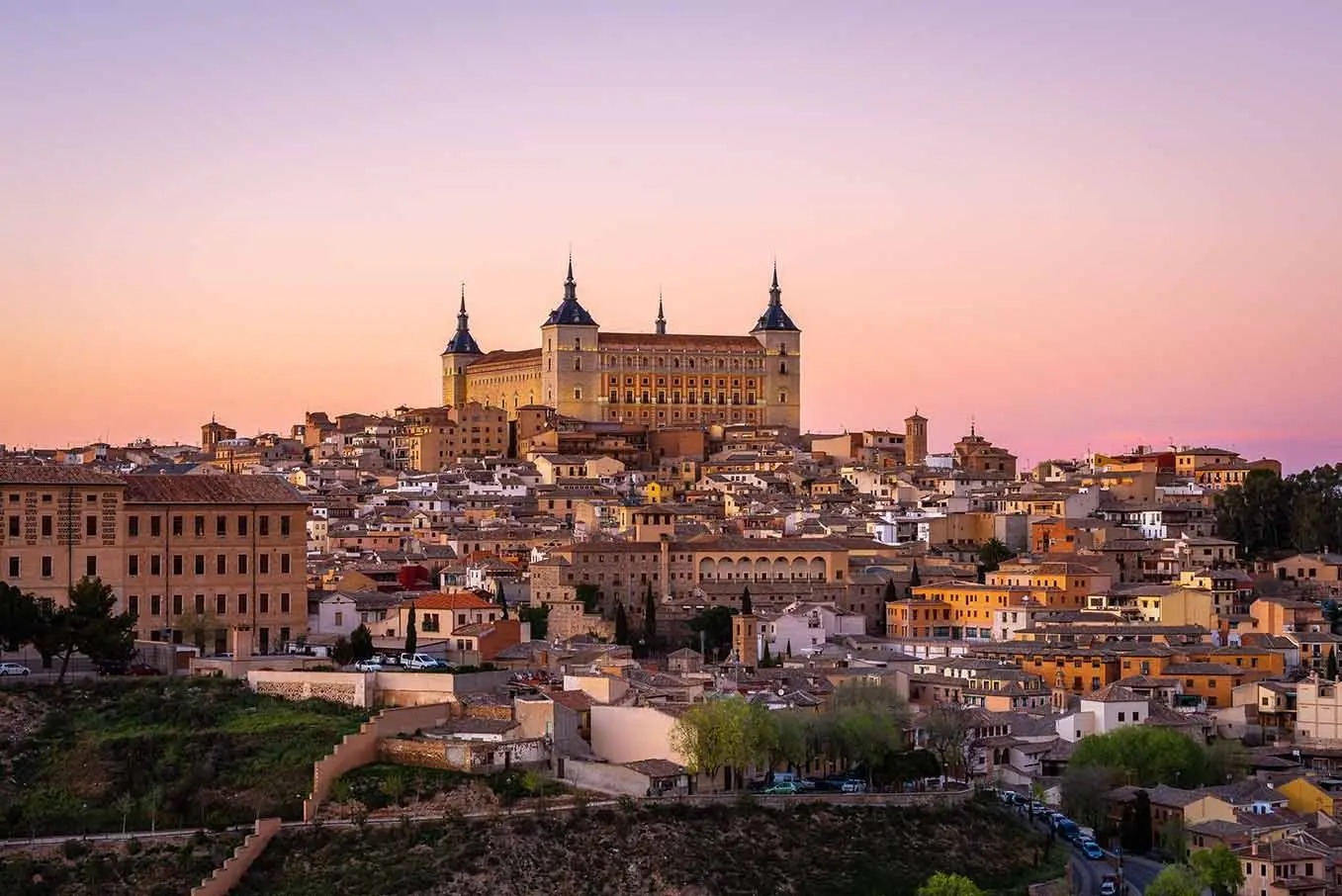 Panoramic view of Toledo, Spain at sunset featuring Alcazar Castle and historic cityscape in Castilla-La Mancha