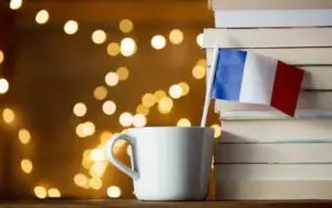 White cup with France flag near books_