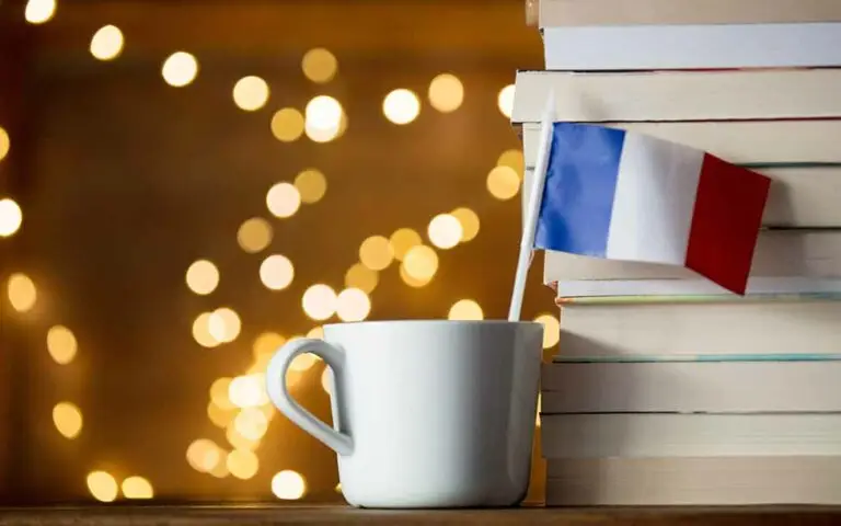 White cup with France flag near books_