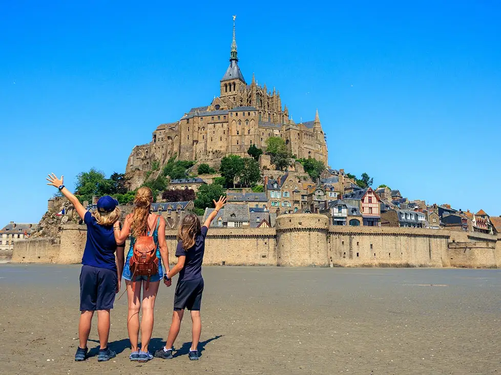 family of mother and two daughters posing outside of Le Mont Saint Michel - Normandy