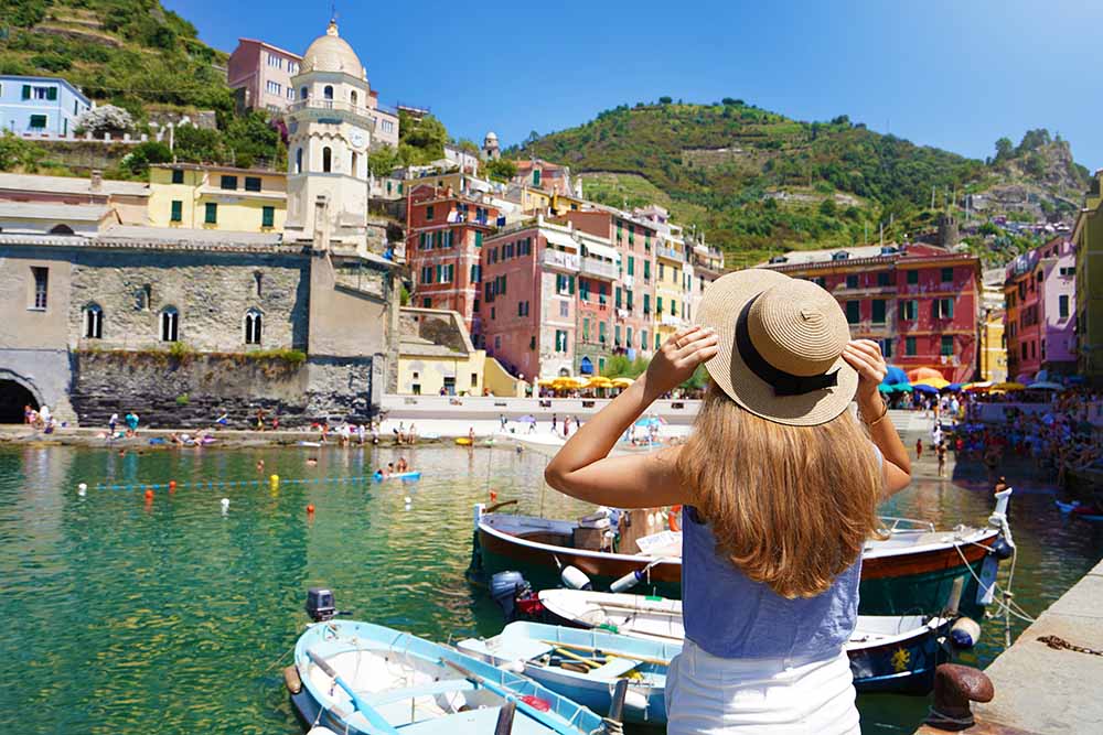 Tourist in Vernazza Cinque Terre Italy viewing colorful buildings and boats by the harbor