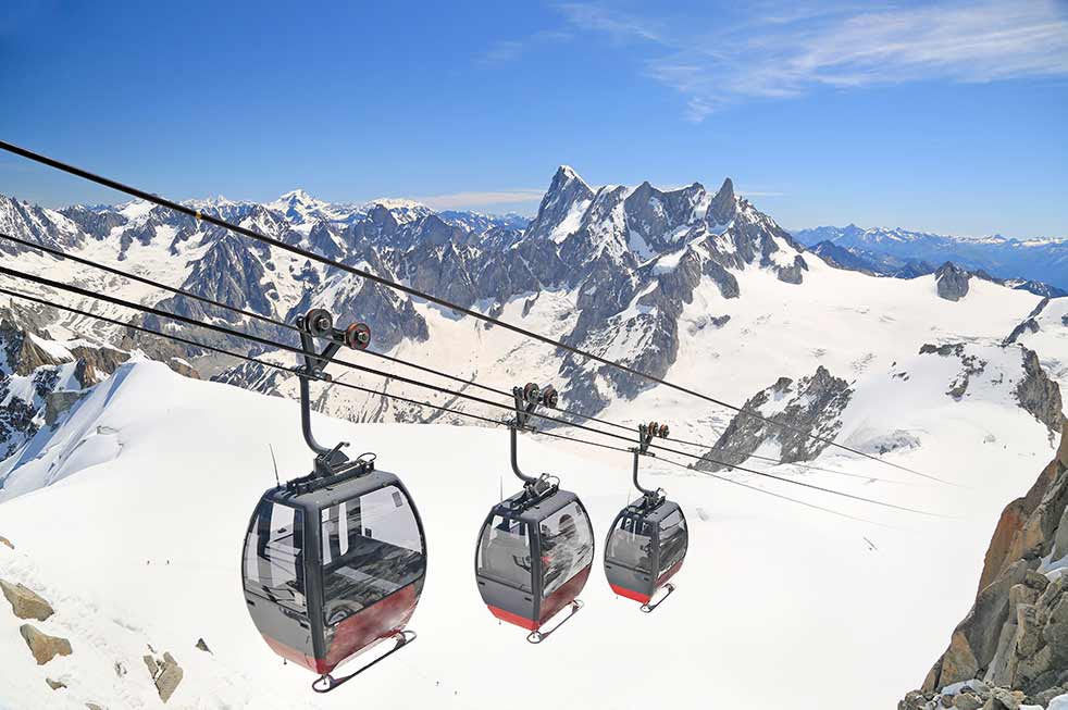 Cable cars ascending the snowy slopes of Aiguille du Midi in the French Alps, showcasing breathtaking mountain views and alpine scenery for tourists in France.