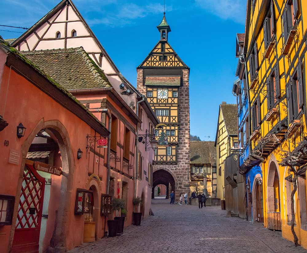 Charming street view in Riquewihr, Alsace, France featuring traditional half-timbered houses and Dolder Tower